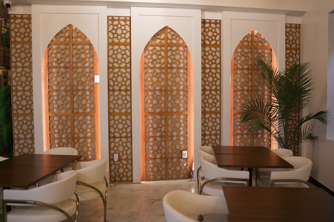 Backlit white mashrabiya arch panels and marble interior at Qahwah Drip