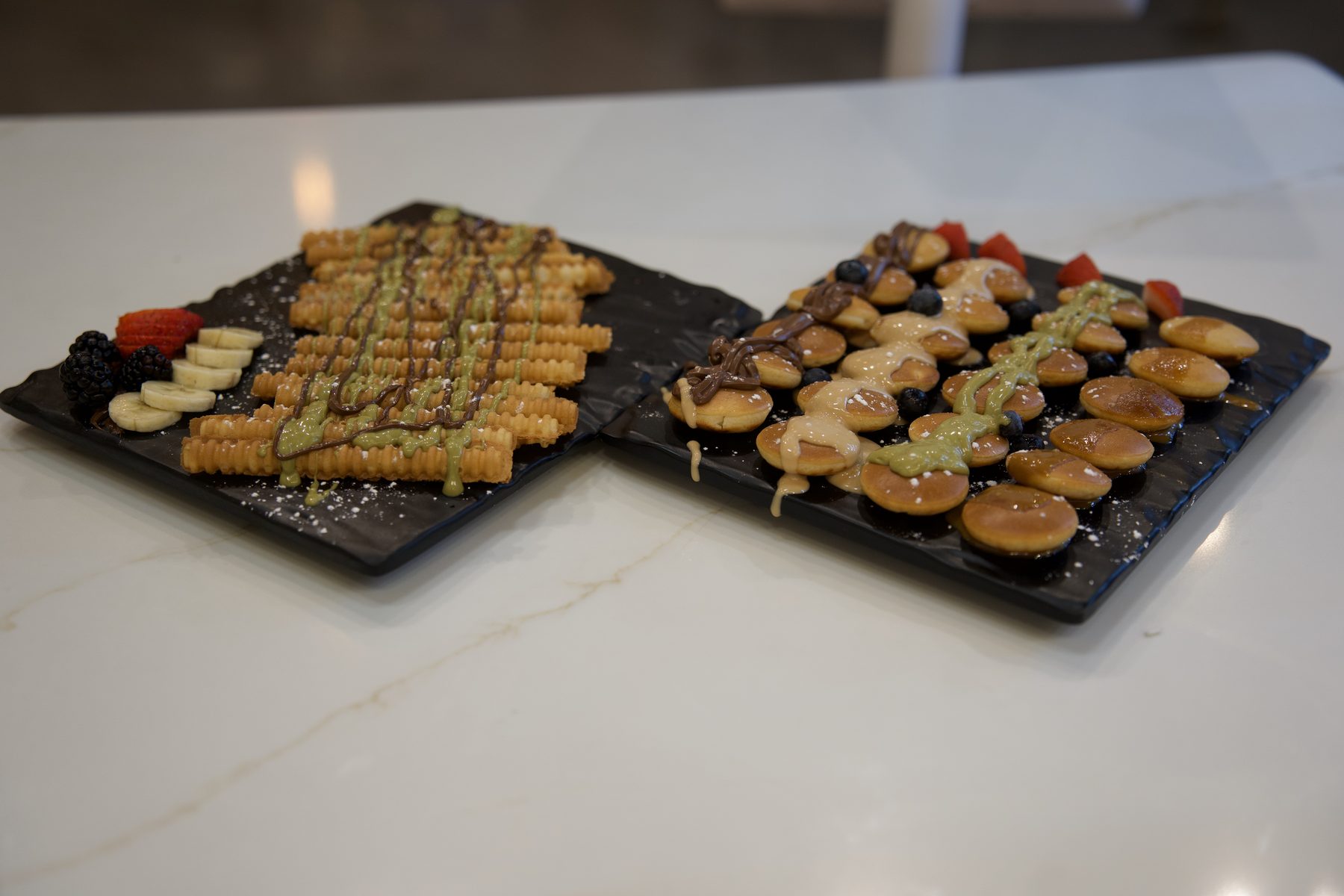 Crispy churros and mini Yemeni pancakes drizzled with chocolate and pistachio, with fresh fruit